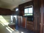 Internal view of living area in a Thorpe Olympian 7.5 ton with dark walnut cabinetry along with faux leather piped seating