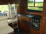 Internal view of 7.5 ton Thorpe Thoroughbred. Finished with dark walnut cabinets complimented by granite effect worktops with slate style flooring. Along with faux leather upholstery this build was commissioned by a client looking for an entirely custom built horsebox.